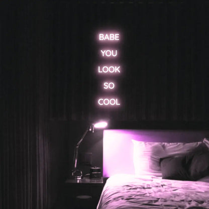 Babe You Look So Cool 2 LED Neon Light Sign in pale pink, featuring five stacked words illuminated above a bed.