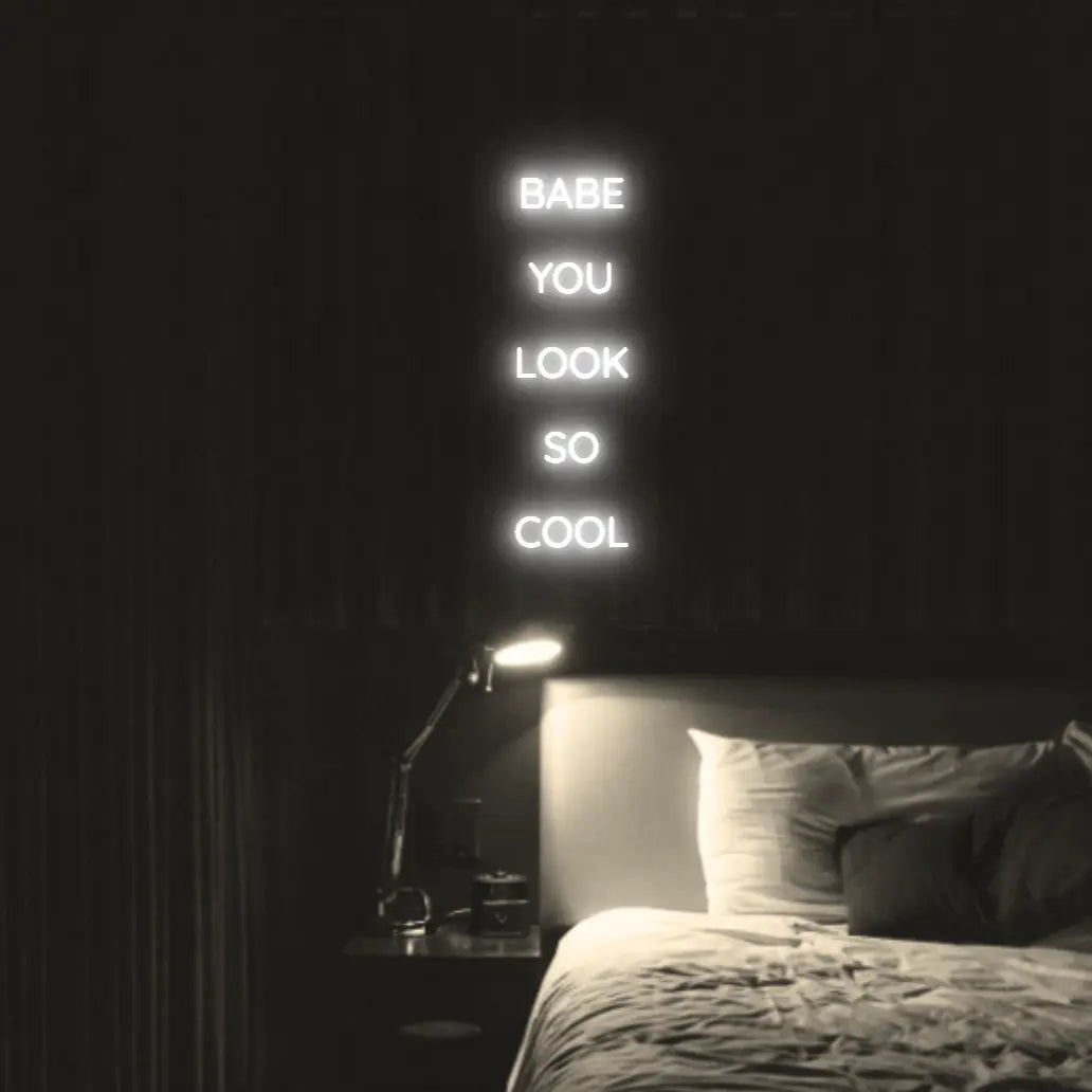 Babe You Look So Cool 2 LED Neon Light Sign in white, featuring five stacked words illuminated above a bed.