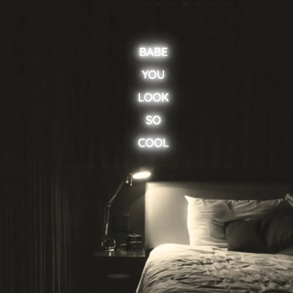 Babe You Look So Cool 2 LED Neon Light Sign in white, featuring five stacked words illuminated above a bed.