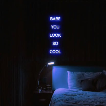 Babe You Look So Cool 2 LED Neon Light Sign in blue, featuring five stacked words illuminated above a bed.
