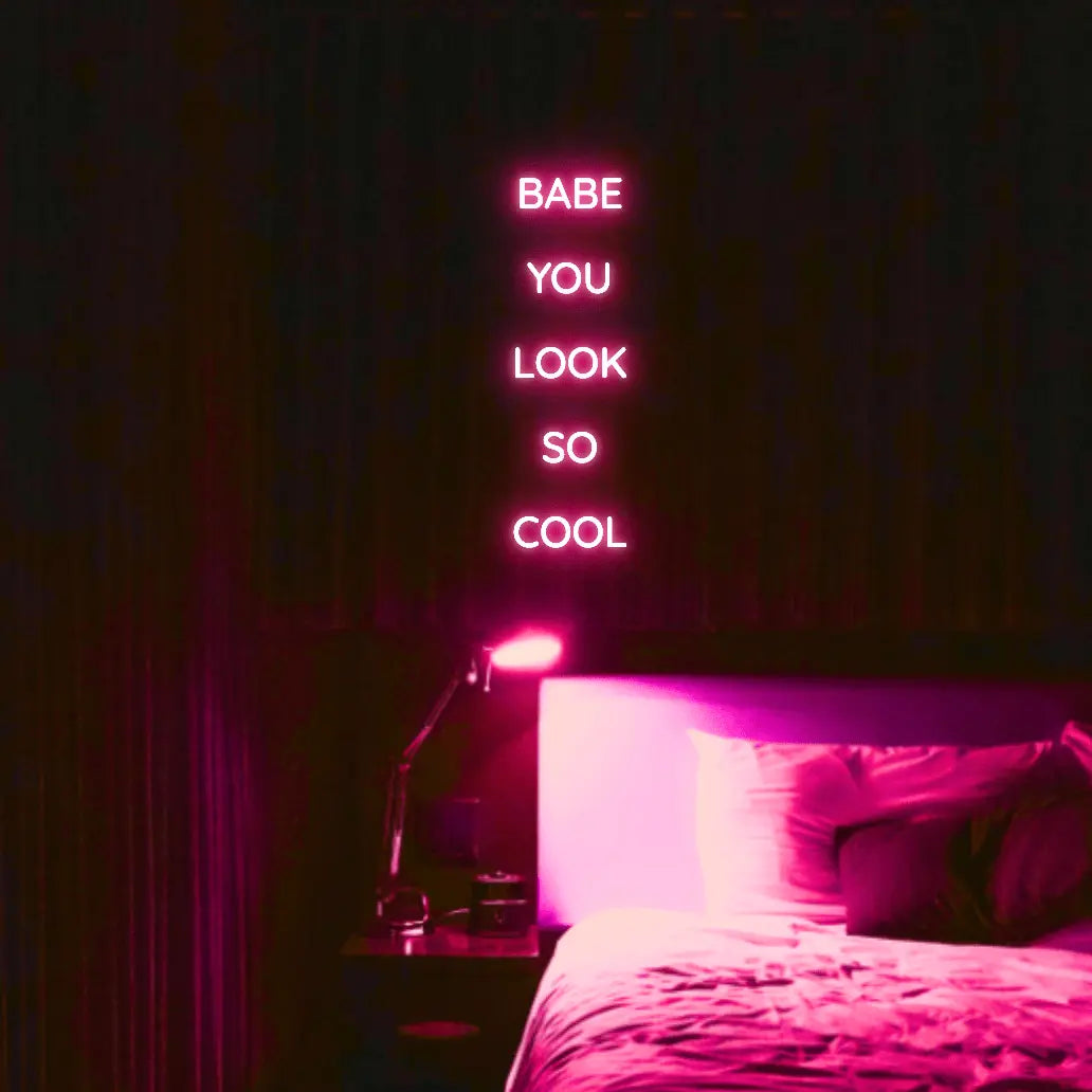 Babe You Look So Cool 2 LED Neon Light Sign in pink, featuring five stacked words illuminated above a bed.