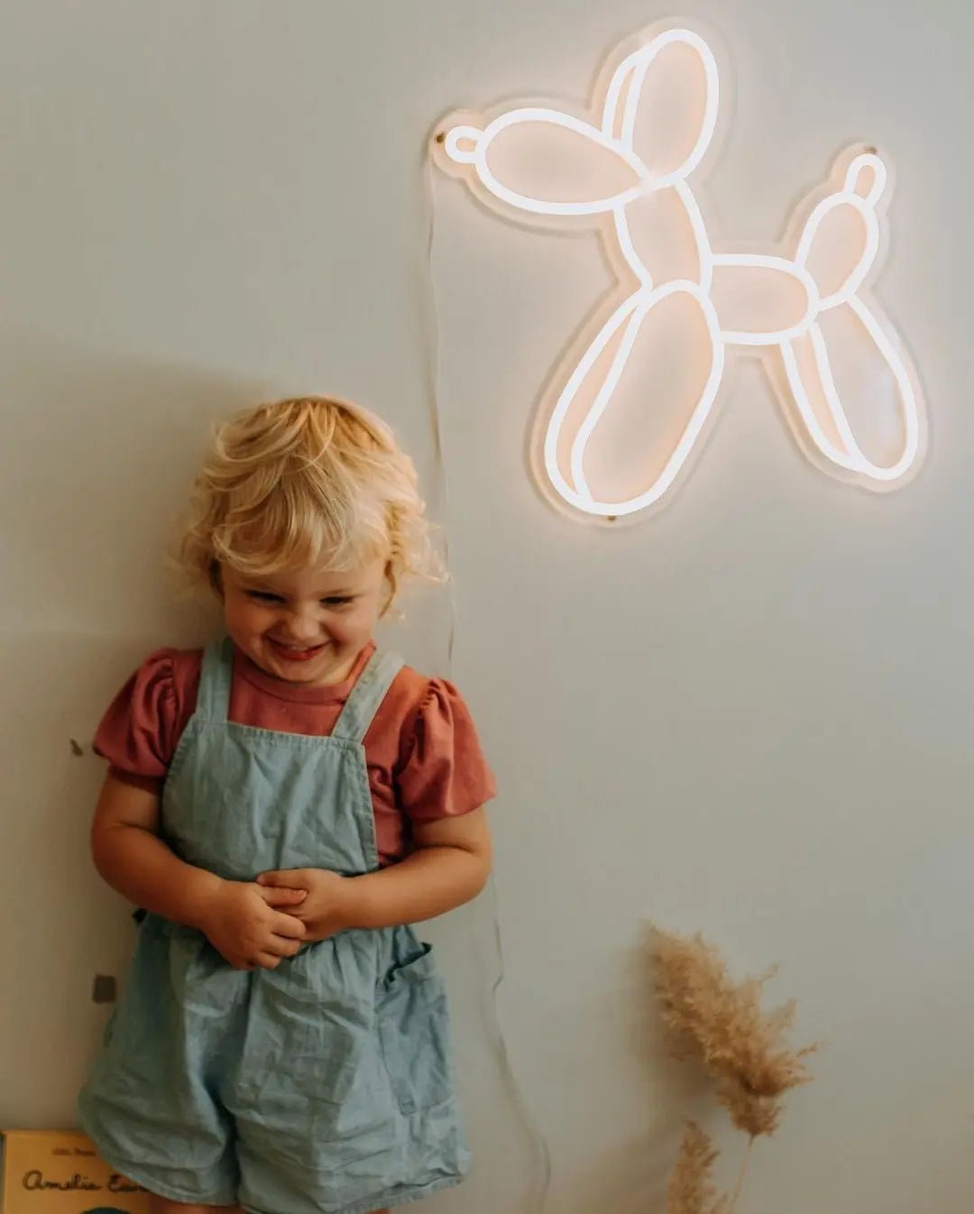 Balloon dog LED Neon Light Sign in warm white, featuring balloon-dog outline on a wall above a child.