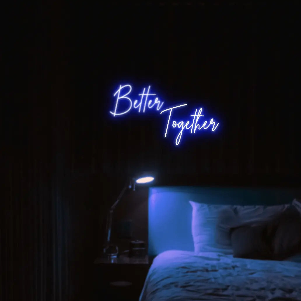 Better Together LED Neon Light Sign in blue, featuring two lines of script lettering illuminated above a bed.