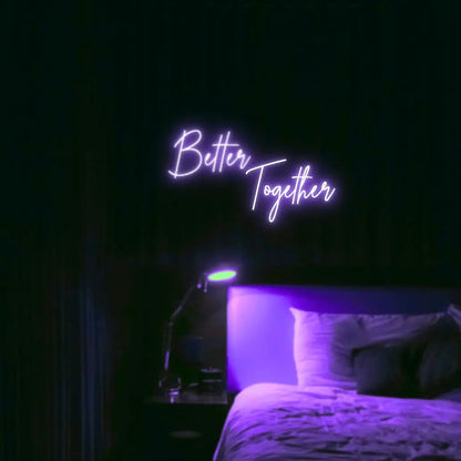 Better Together LED Neon Light Sign in purple, featuring two lines of script lettering illuminated above a bed.