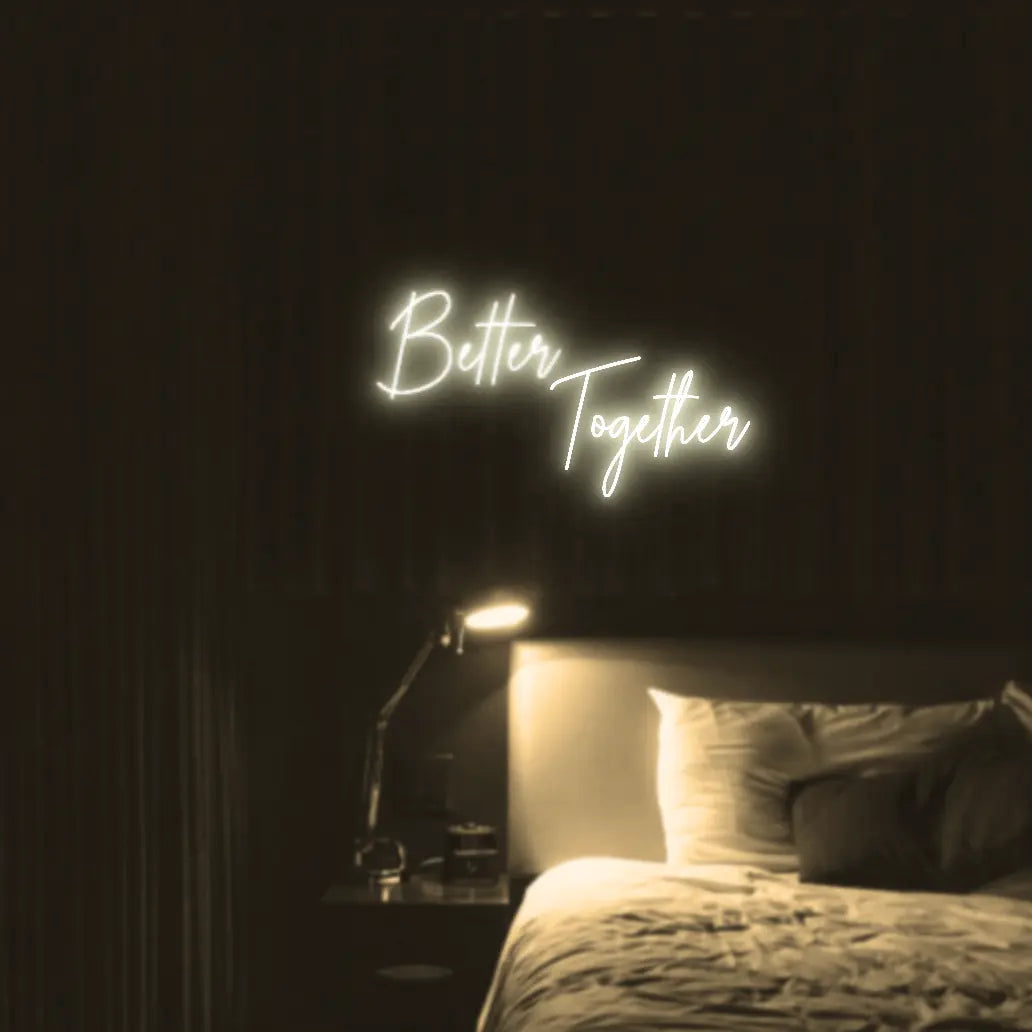 Better Together LED Neon Light Sign in warm white, featuring two lines of script lettering illuminated above a bed.