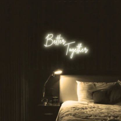 Better Together LED Neon Light Sign in warm white, featuring two lines of script lettering illuminated above a bed.