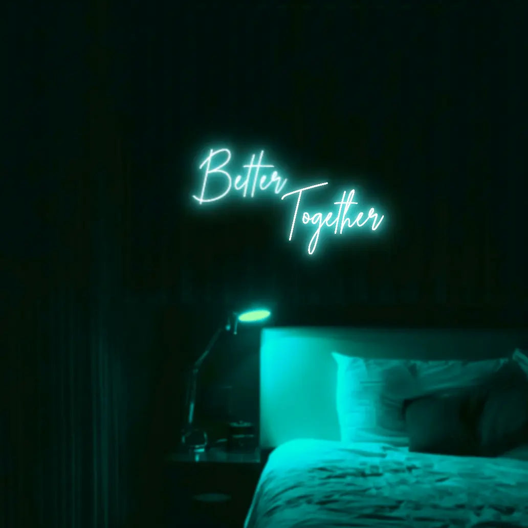 Better Together LED Neon Light Sign in turquoise, featuring two lines of script lettering illuminated above a bed.