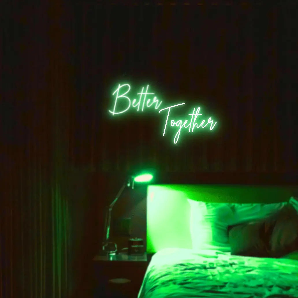 Better Together LED Neon Light Sign in green, featuring two lines of script lettering illuminated above a bed.