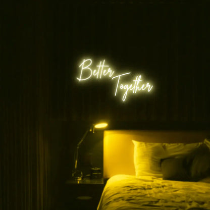 Better Together LED Neon Light Sign in yellow, featuring two lines of script lettering illuminated above a bed.