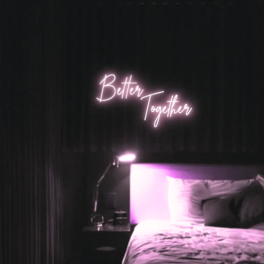 Better Together LED Neon Light Sign in pale pink, featuring two lines of script lettering illuminated above a bed.