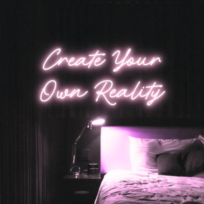 Create Your Own Reality LED Neon Light Sign in pale pink, featuring two lines of script lettering illuminated above a bed.