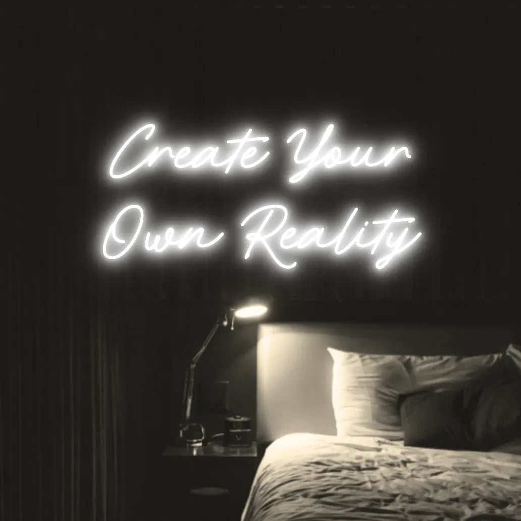 Create Your Own Reality LED Neon Light Sign in white, featuring two lines of script lettering illuminated above a bed.