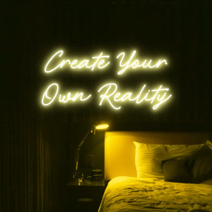 Create Your Own Reality LED Neon Light Sign in yellow, featuring two lines of script lettering illuminated above a bed.