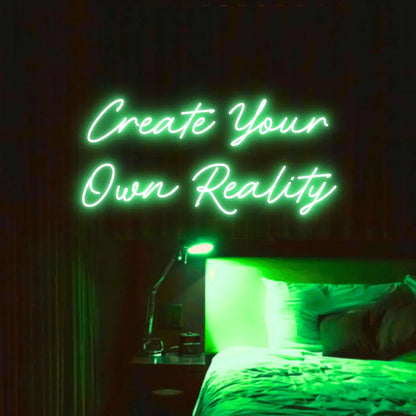 Create Your Own Reality LED Neon Light Sign in green, featuring two lines of script lettering illuminated above a bed.