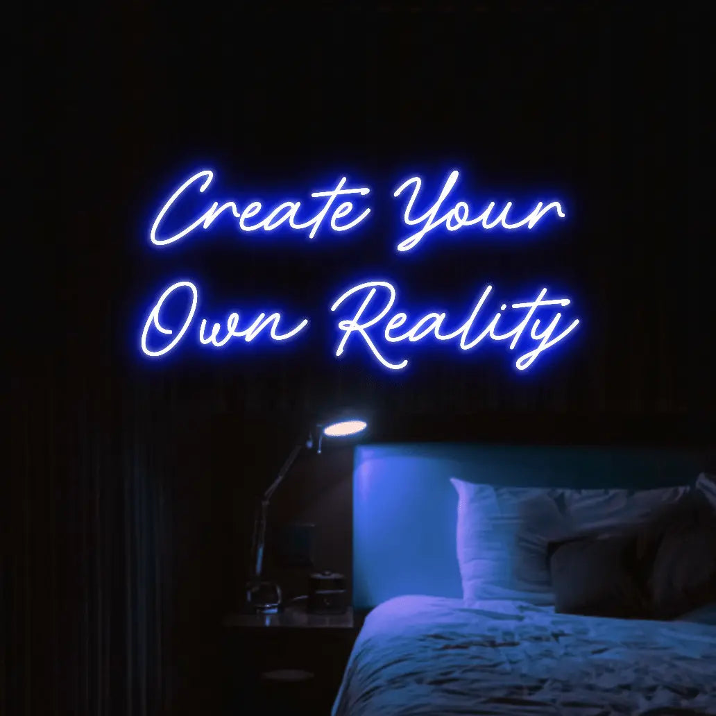 Create Your Own Reality LED Neon Light Sign in blue, featuring two lines of script lettering illuminated above a bed.