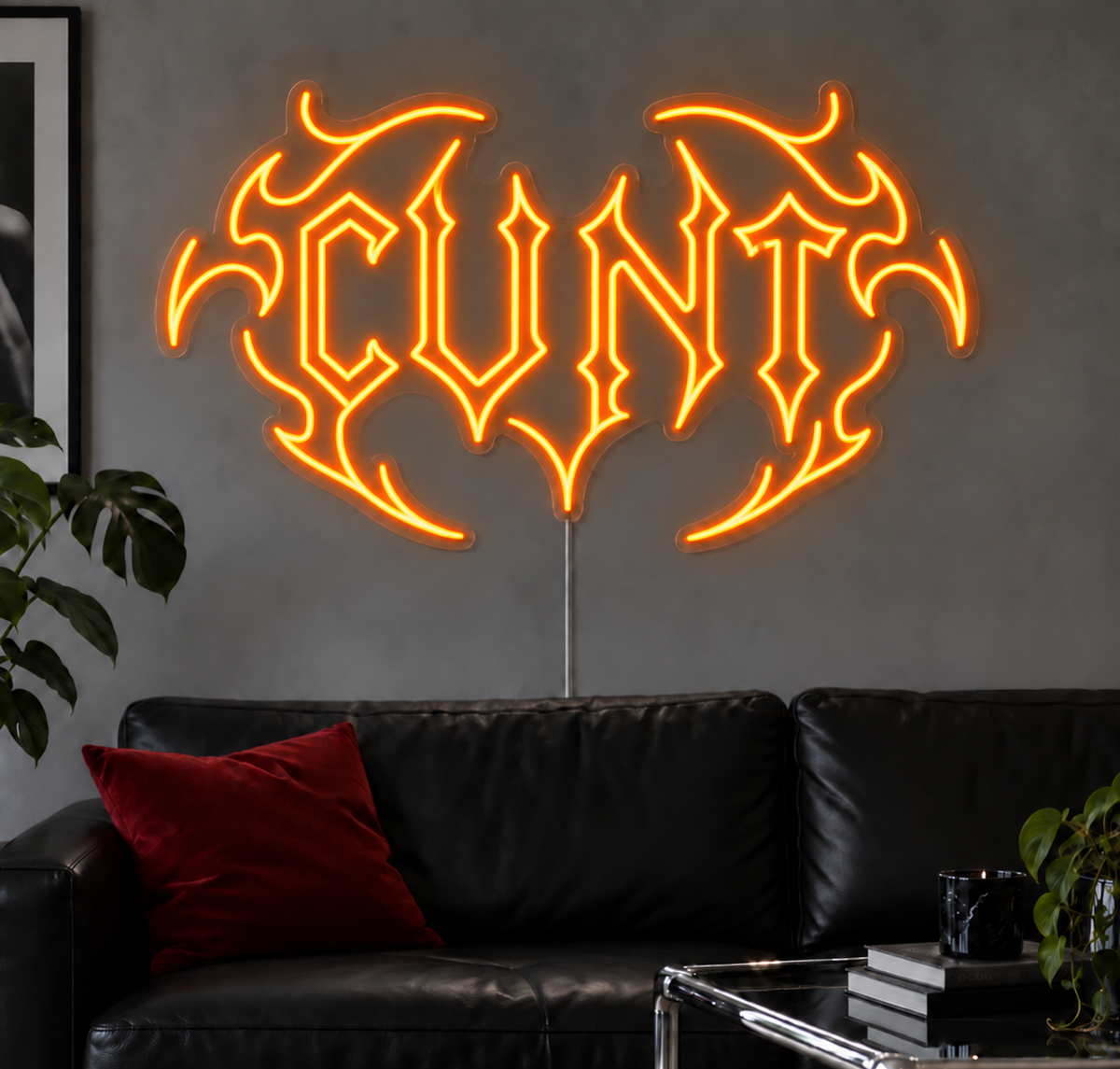 Cunt Neon Sign in Orange LED neon with double outlined C, displayed above a black leather sofa.