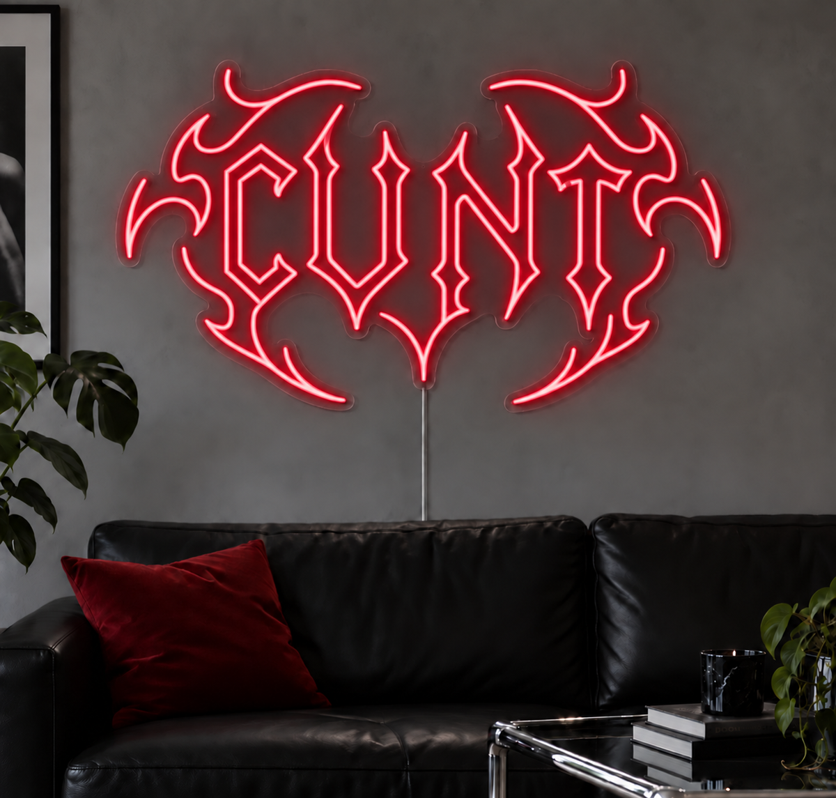 Cunt Neon Sign in Rose Red LED neon with double outlined C, displayed above a black leather sofa.