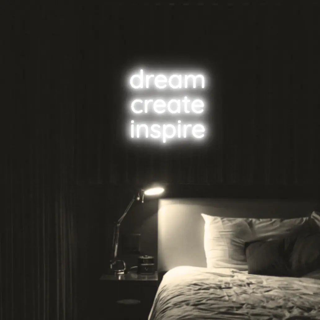 Dream Create Inspire LED Neon Light Sign in white, featuring three lines of lettering illuminated above a bed.