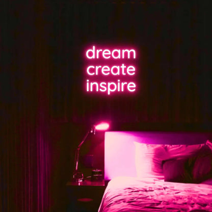 Dream Create Inspire LED Neon Light Sign in pink, featuring three lines of lettering illuminated above a bed.