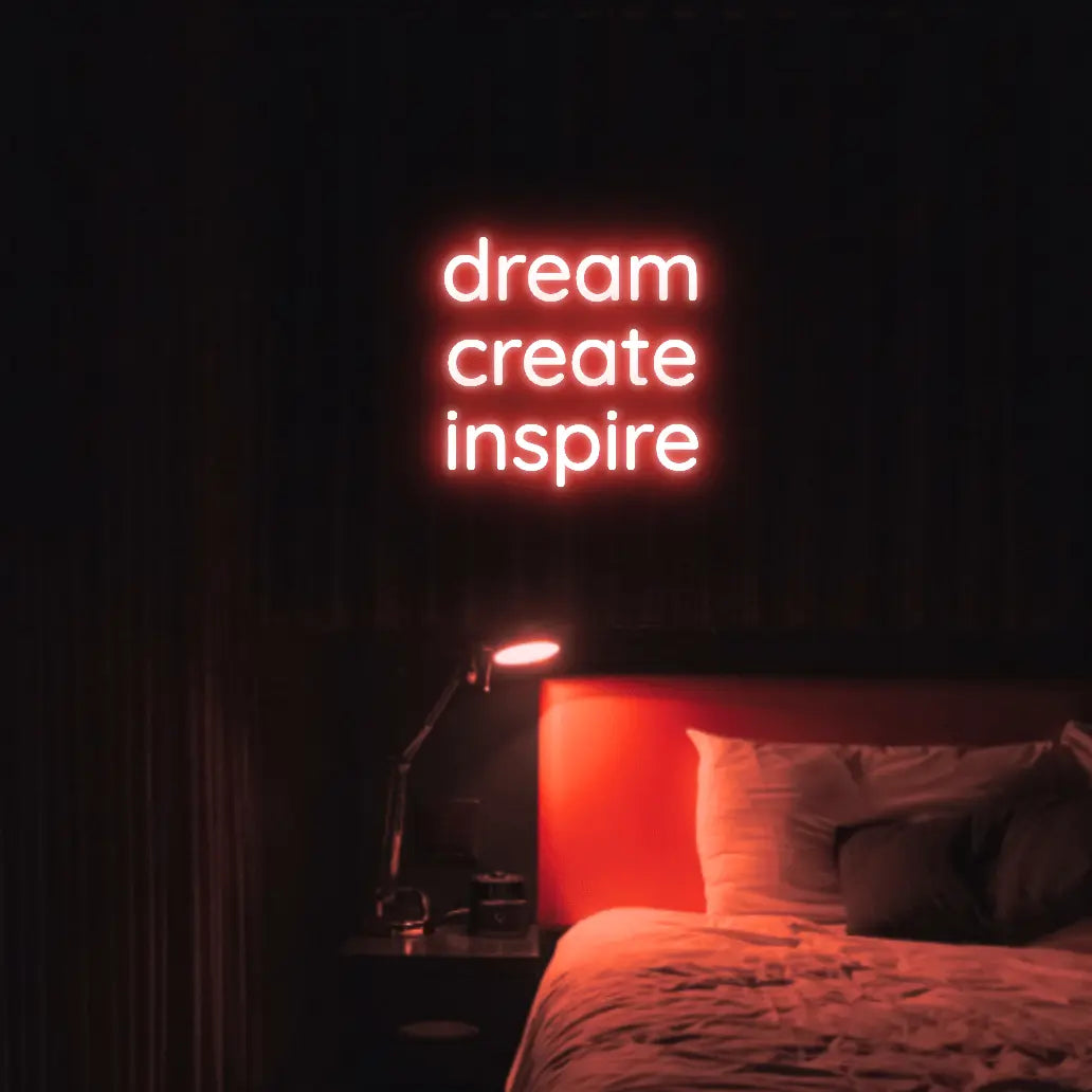 Dream Create Inspire LED Neon Light Sign in red, featuring three lines of lettering illuminated above a bed.