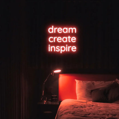 Dream Create Inspire LED Neon Light Sign in red, featuring three lines of lettering illuminated above a bed.
