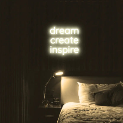 Dream Create Inspire LED Neon Light Sign in warm white, featuring three lines of lettering illuminated above a bed.