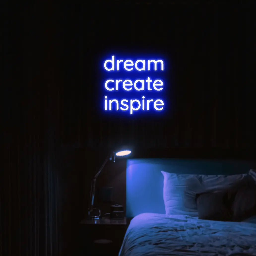 Dream Create Inspire LED Neon Light Sign in blue, featuring three lines of lettering illuminated above a bed.