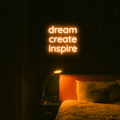 Dream Create Inspire LED Neon Light Sign in orange, featuring three lines of lettering illuminated above a bed.