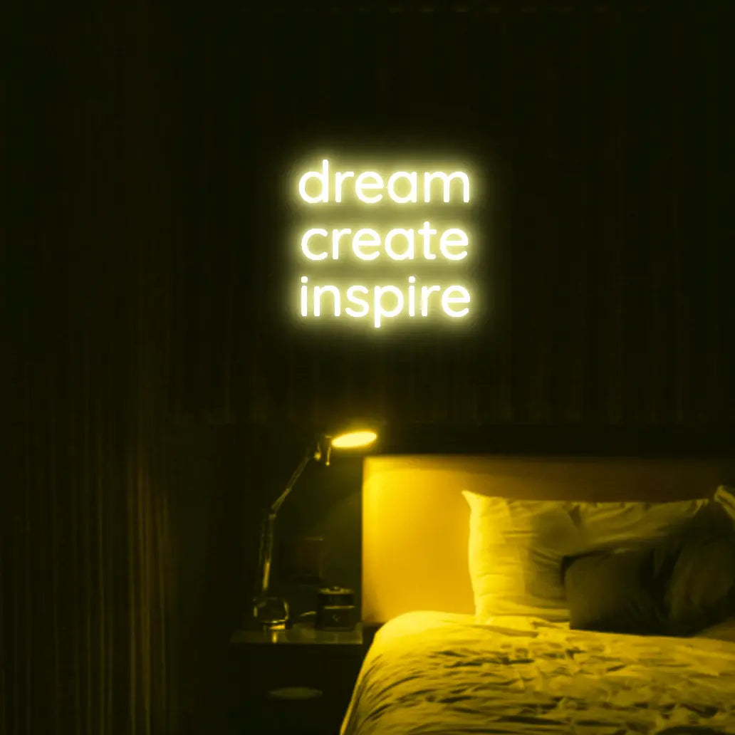 Dream Create Inspire LED Neon Light Sign in yellow, featuring three lines of lettering illuminated above a bed.