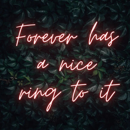 Forever Has a Nice Ring to It LED Neon Light Sign in red, featuring three lines of script lettering against a dark foliage backdrop.