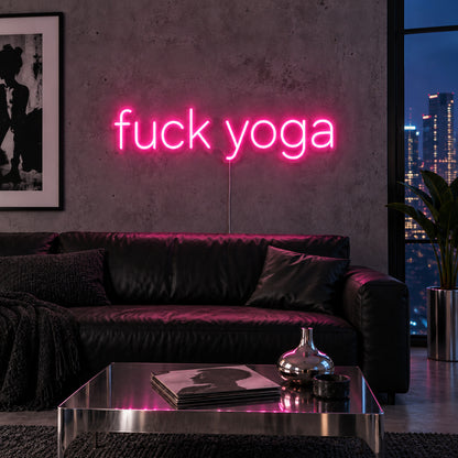 Rose Red version of the Fuck Yoga Neon Sign, shown above a black leather sofa.