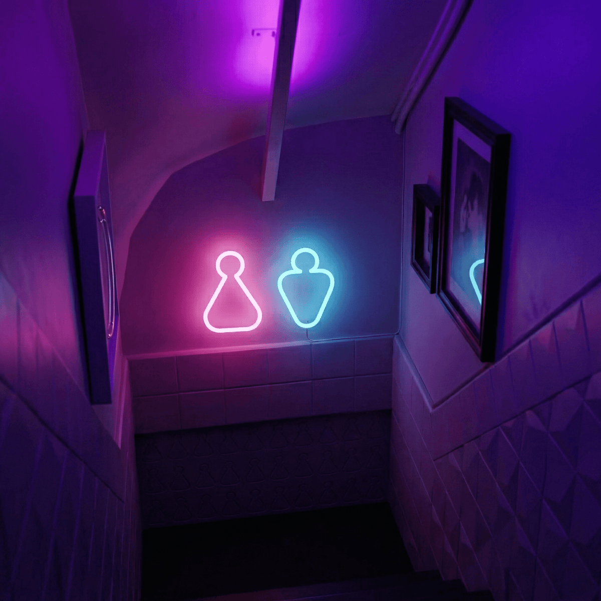 Girls and Boys Bathrooms LED Neon Sign in pink and blue, featuring female and male bathroom symbols on a dark interior wall.