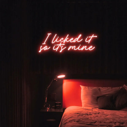 I Licked It So Its Mine LED Neon Light Sign in red, featuring two lines of script lettering illuminated above a bed.
