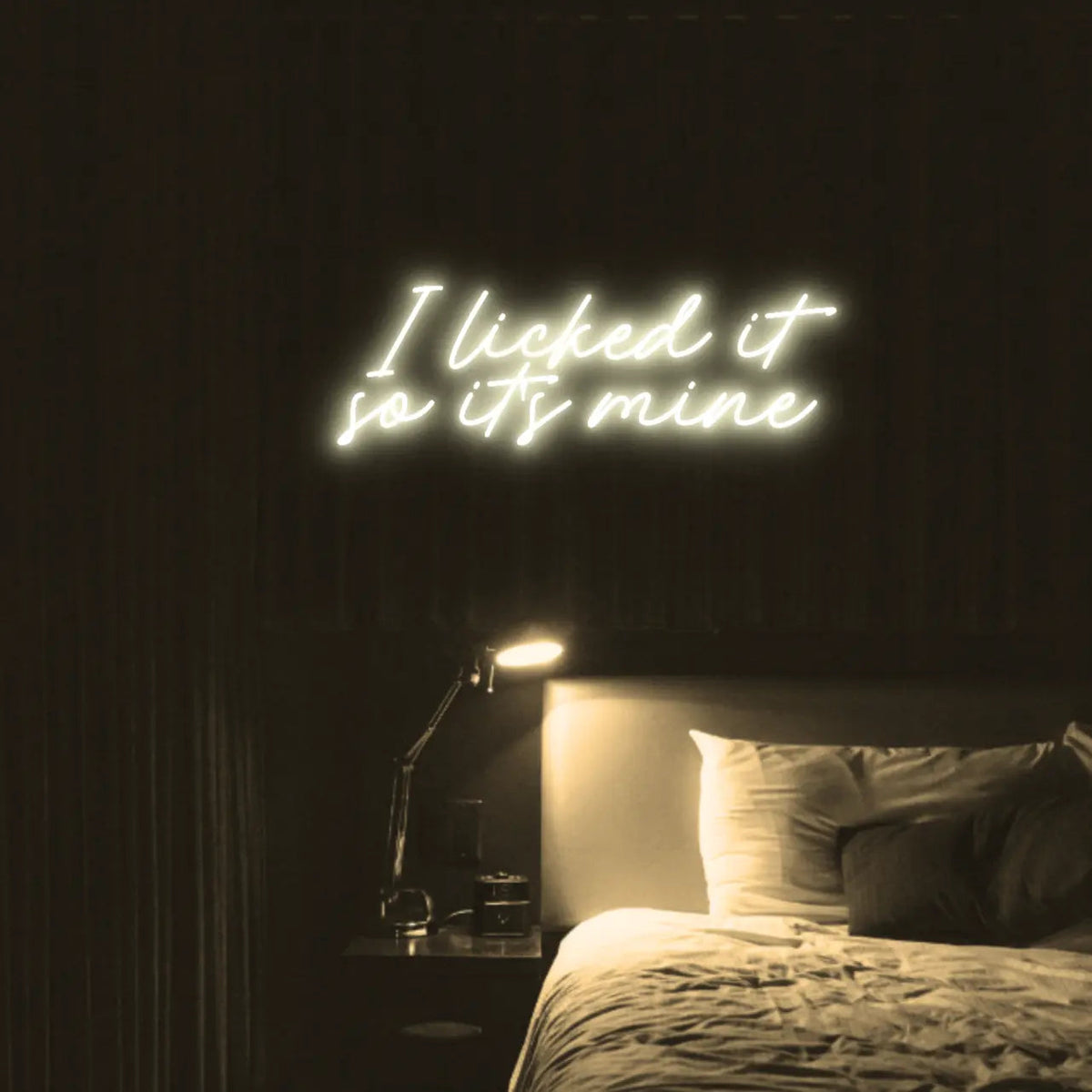 I Licked It So Its Mine LED Neon Light Sign in warm white, featuring two lines of script lettering illuminated above a bed.