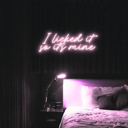 I Licked It So Its Mine LED Neon Light Sign in pale pink, featuring two lines of script lettering illuminated above a bed.