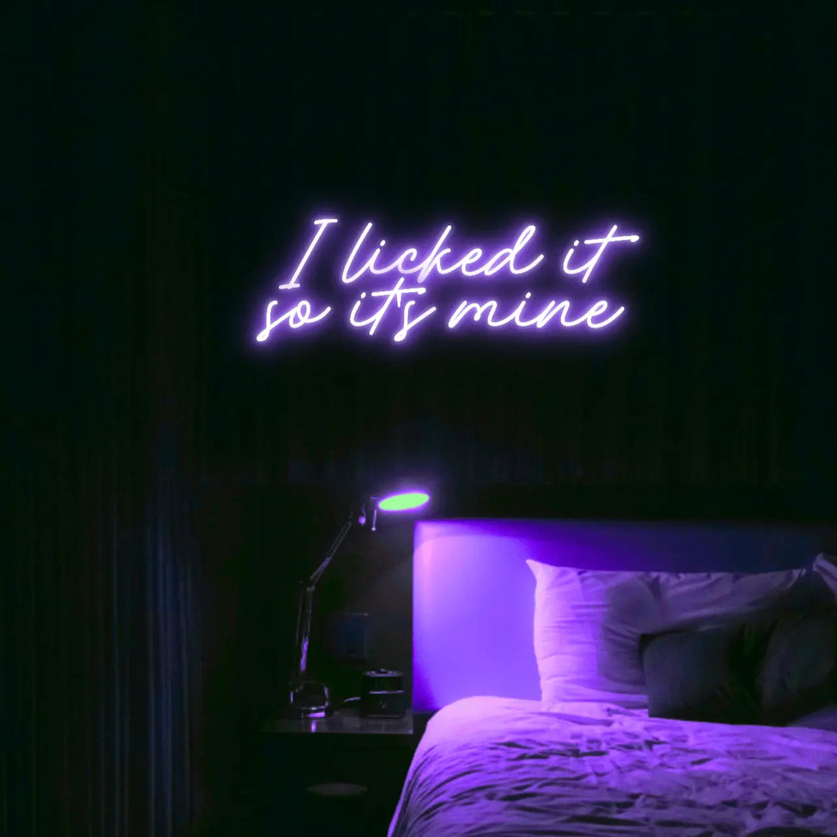 I Licked It So Its Mine LED Neon Light Sign in purple, featuring two lines of script lettering illuminated above a bed.