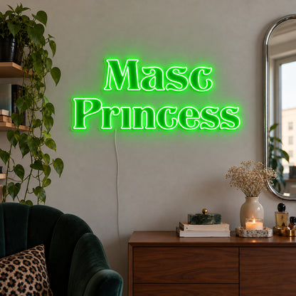 Masc Princess Neon Sign with green lighting, displayed above a wooden sideboard beside a green chair.