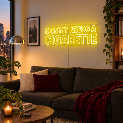 Mommy Needs A Cigarette Neon Sign with yellow lighting, displayed above a brown sofa.