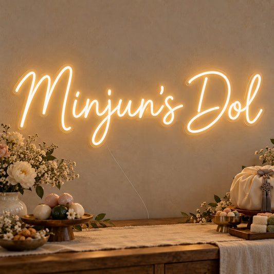 Personalised Dol Neon Sign on clear cut-to-shape acrylic, illuminated on a wall in a styled celebration setting; sample personalised wording shown