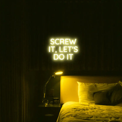 Screw It, Let's Do It LED Neon Light Sign in yellow, featuring stacked block lettering illuminated above a bed.