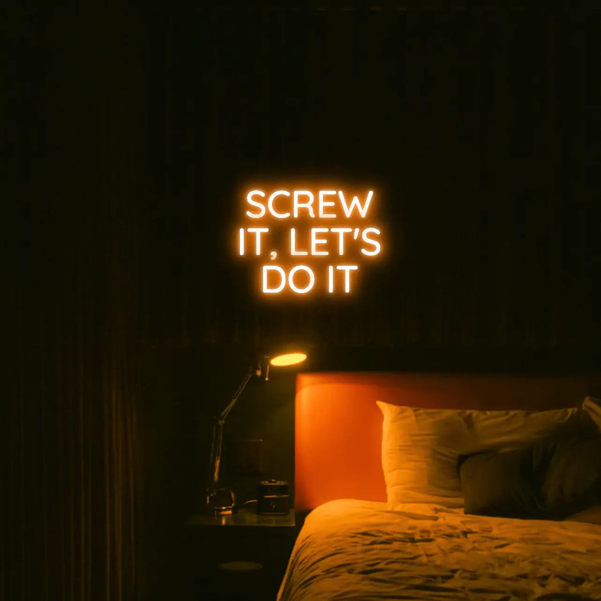 Screw It, Let's Do It LED Neon Light Sign in orange, featuring stacked block lettering illuminated above a bed.