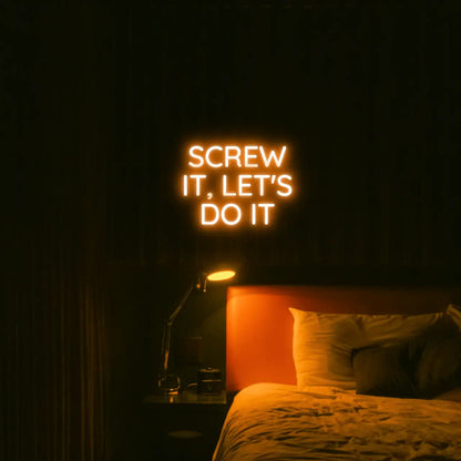 Screw It, Let's Do It LED Neon Light Sign in orange, featuring stacked block lettering illuminated above a bed.