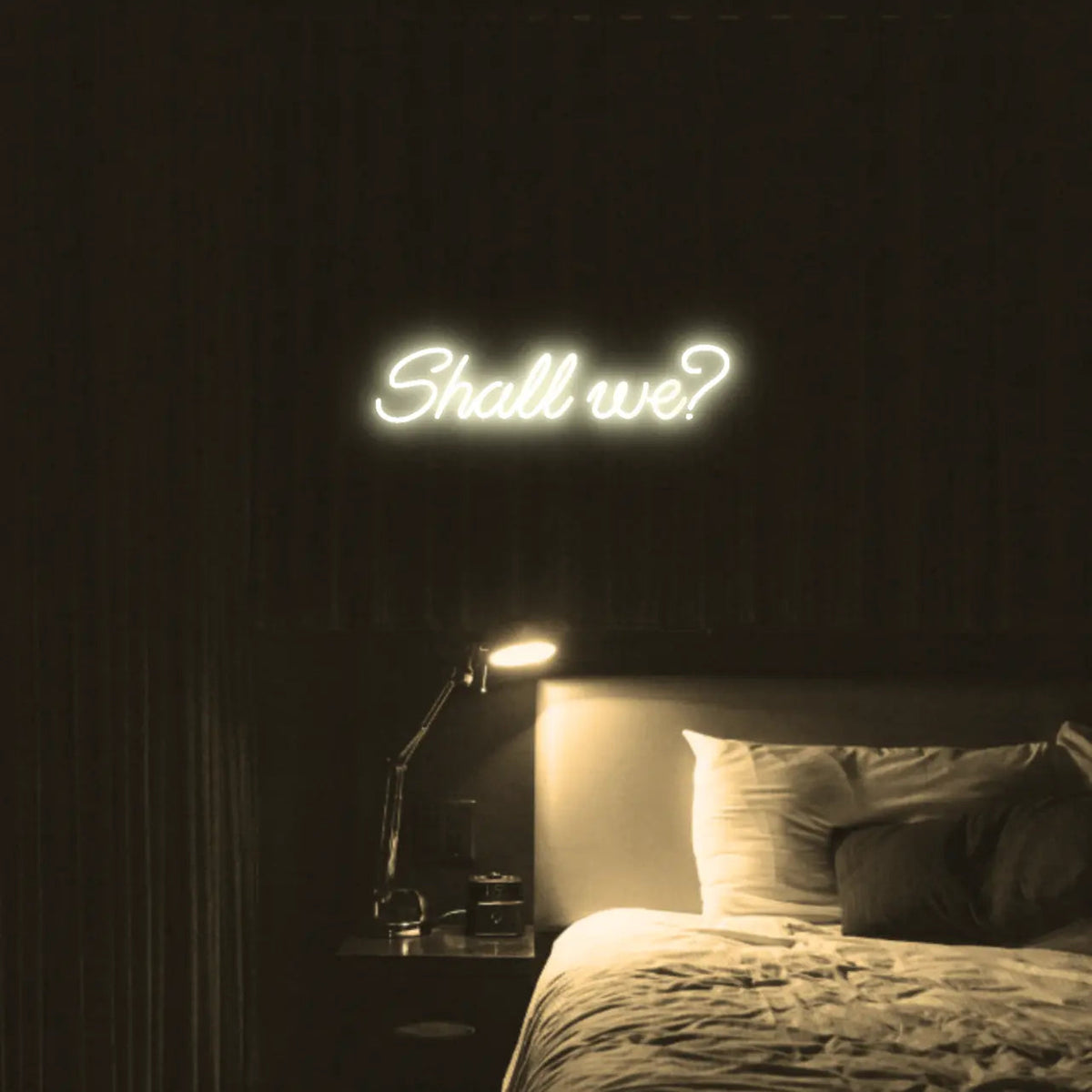 Shall we? LED Neon Light Sign in warm white, featuring script lettering illuminated above a bed.