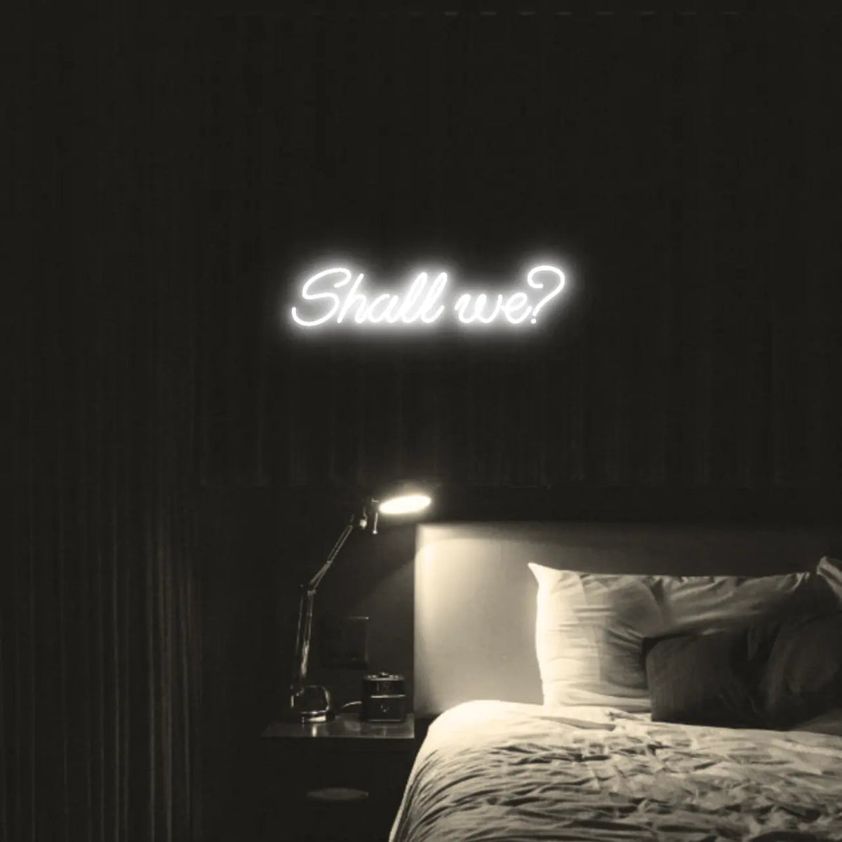 Shall we? LED Neon Light Sign in white, featuring script lettering illuminated above a bed.