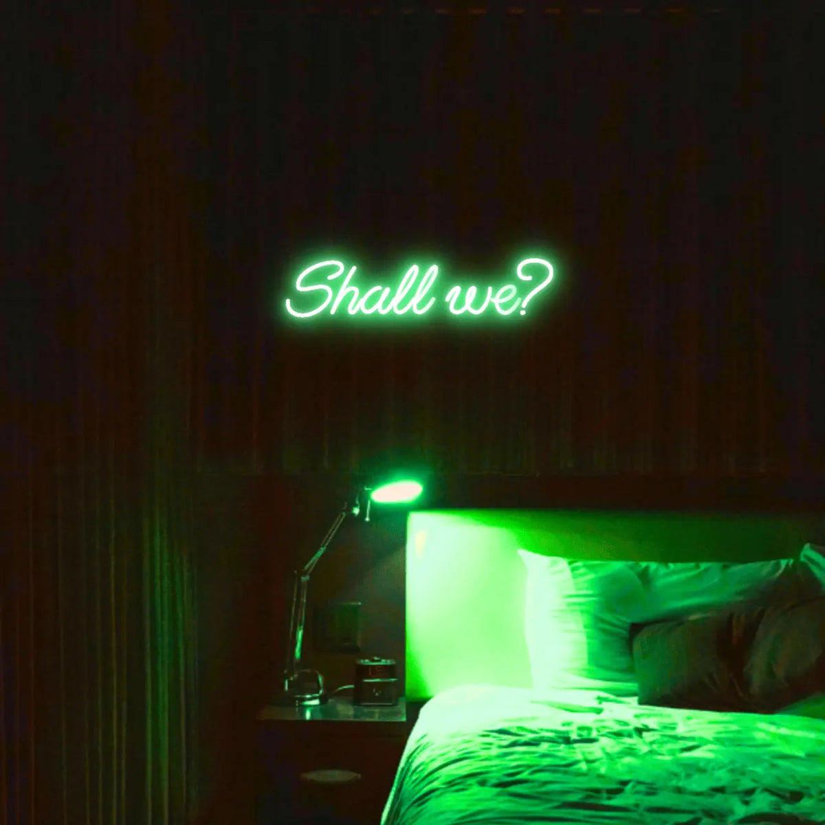 Shall we? LED Neon Light Sign in green, featuring script lettering illuminated above a bed.