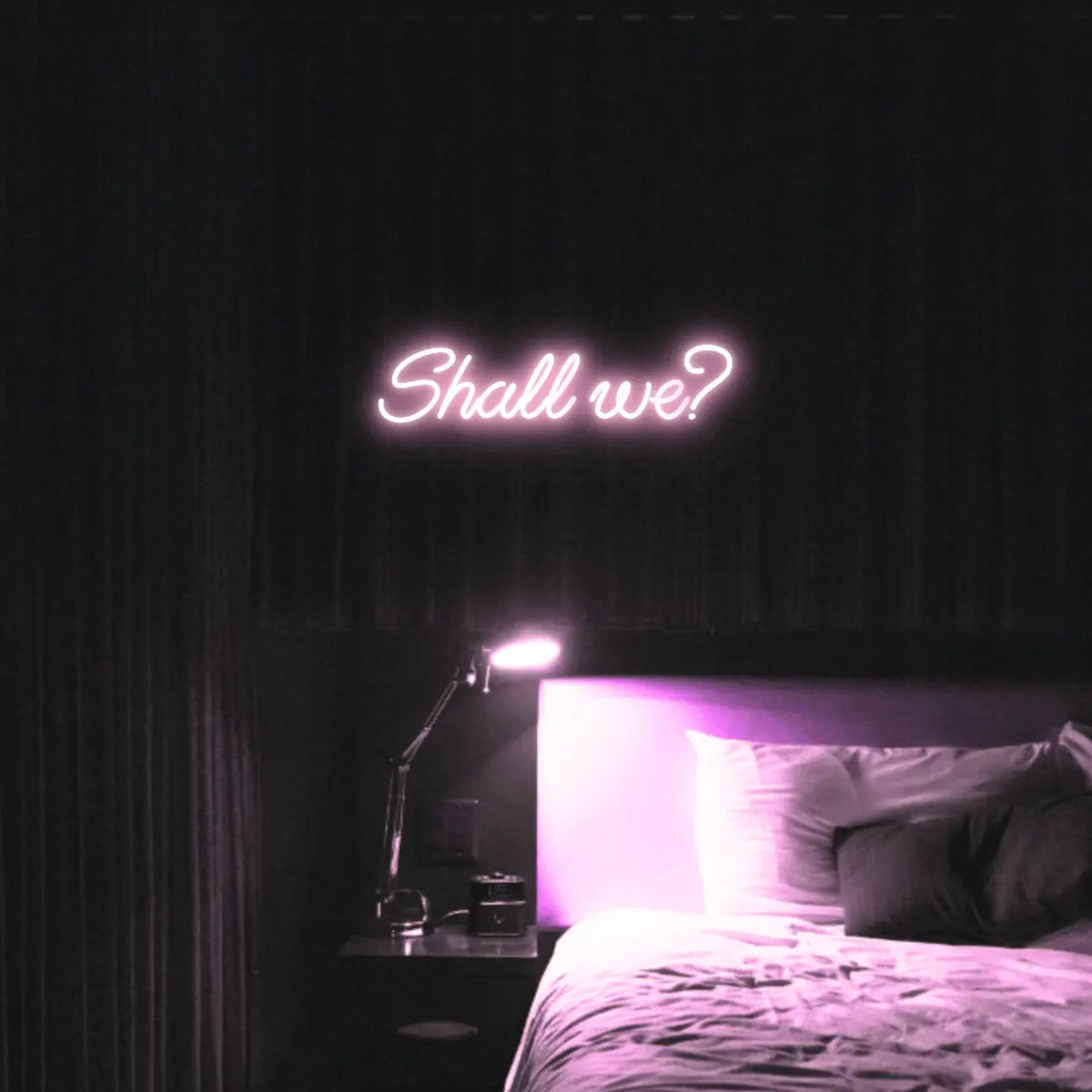 Shall we? LED Neon Light Sign in pale pink, featuring script lettering illuminated above a bed.