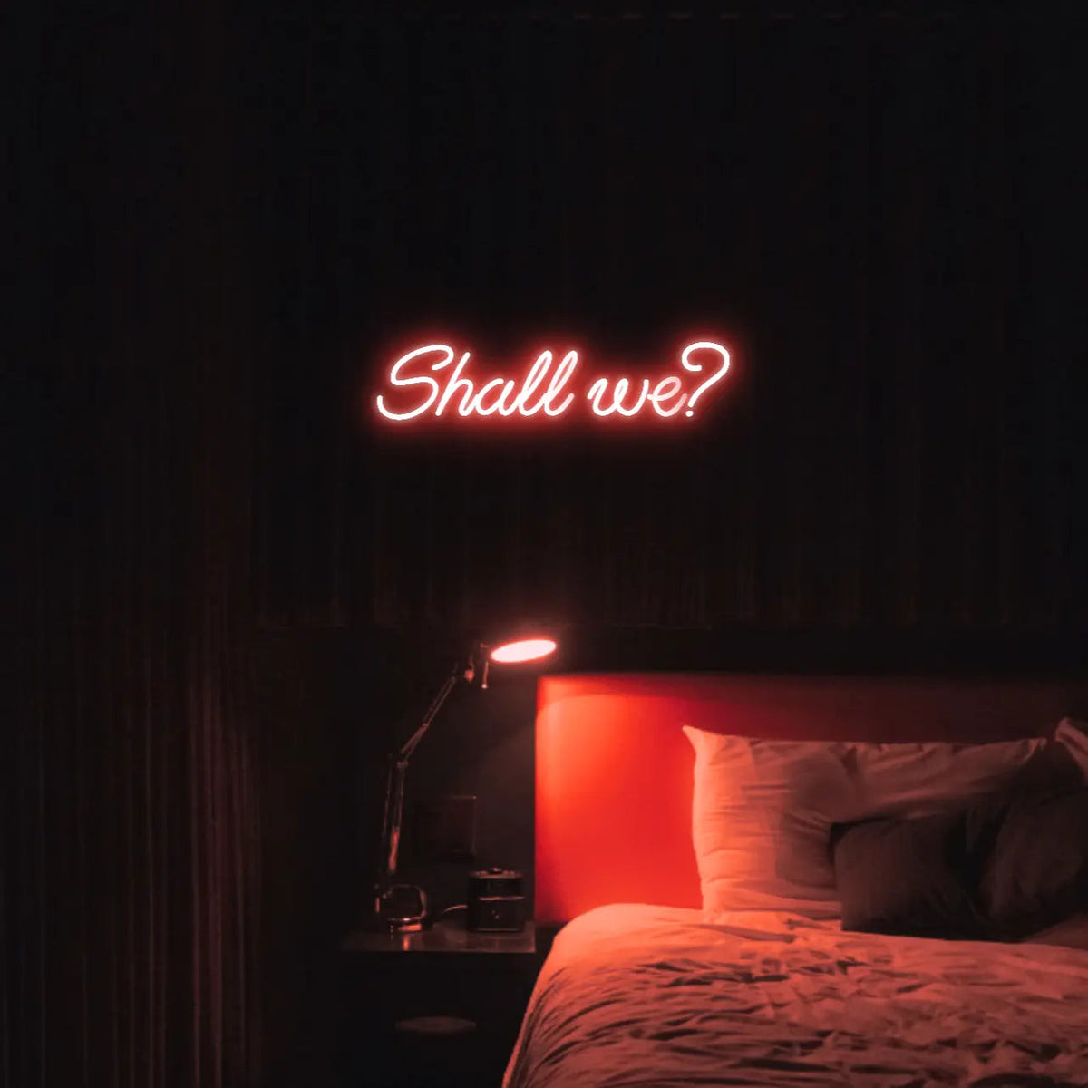 Shall we? LED Neon Light Sign in red, featuring script lettering illuminated above a bed.