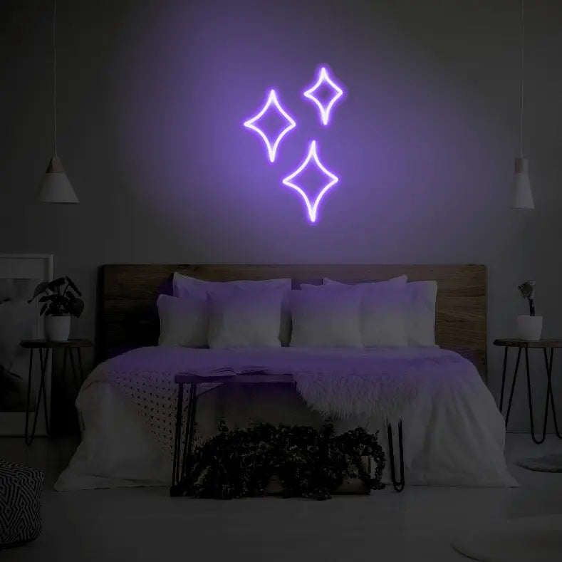 Sparkle LED Neon Light Sign in purple, featuring three outlined sparkle shapes illuminated above a bed.
