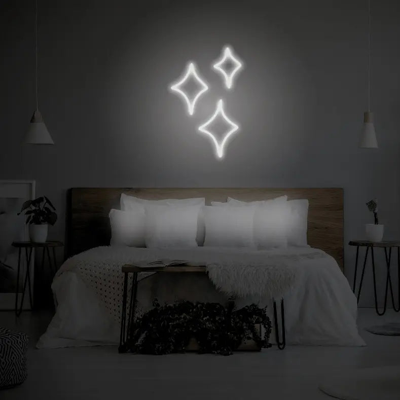 Sparkle LED Neon Light Sign in white, featuring three outlined sparkle shapes illuminated above a bed.