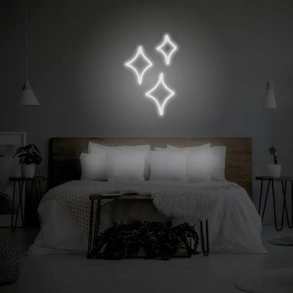 Sparkle LED Neon Light Sign in white, featuring three outlined sparkle shapes illuminated above a bed.